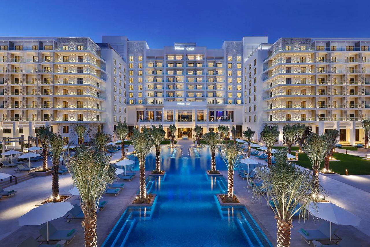The geometric outdoor pool at Hilton Abu Dhabi Yas Island overlooking the Yas Bay waterfront at sunset.