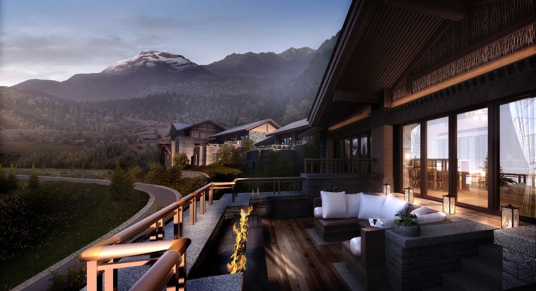 A stone-walled villa terrace at Rissai Valley with a fire pit, overlooking the snow-capped Minshan mountains at dusk.
