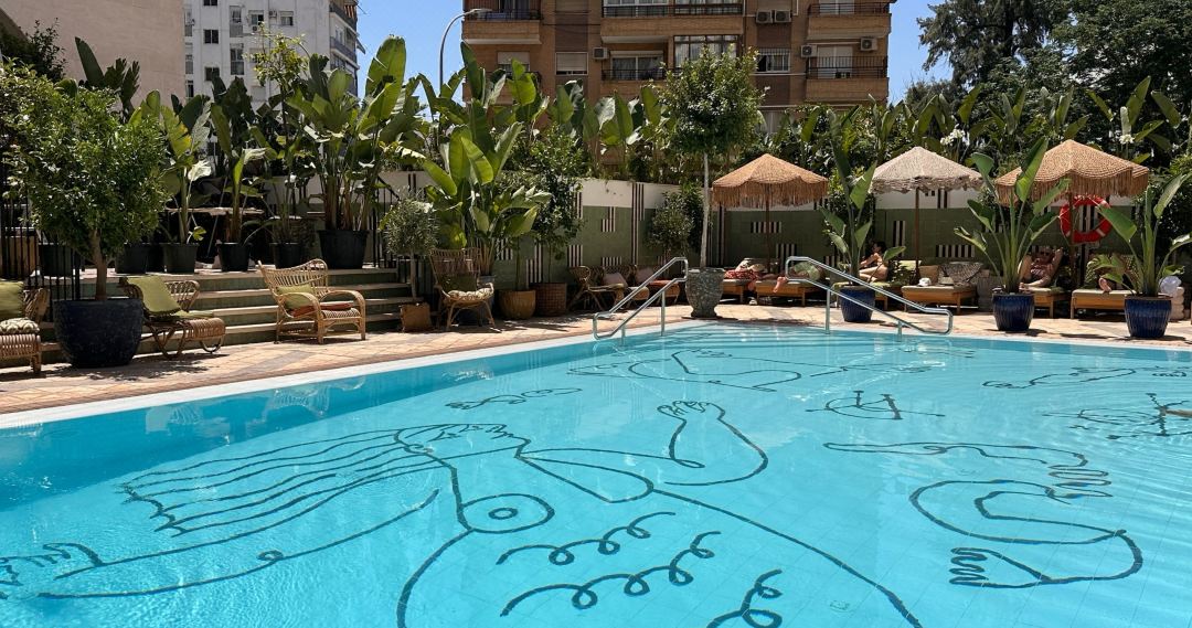 A sun-drenched pool deck with Mediterranean blue tiling and white loungers at Only YOU Hotel Sevilla.