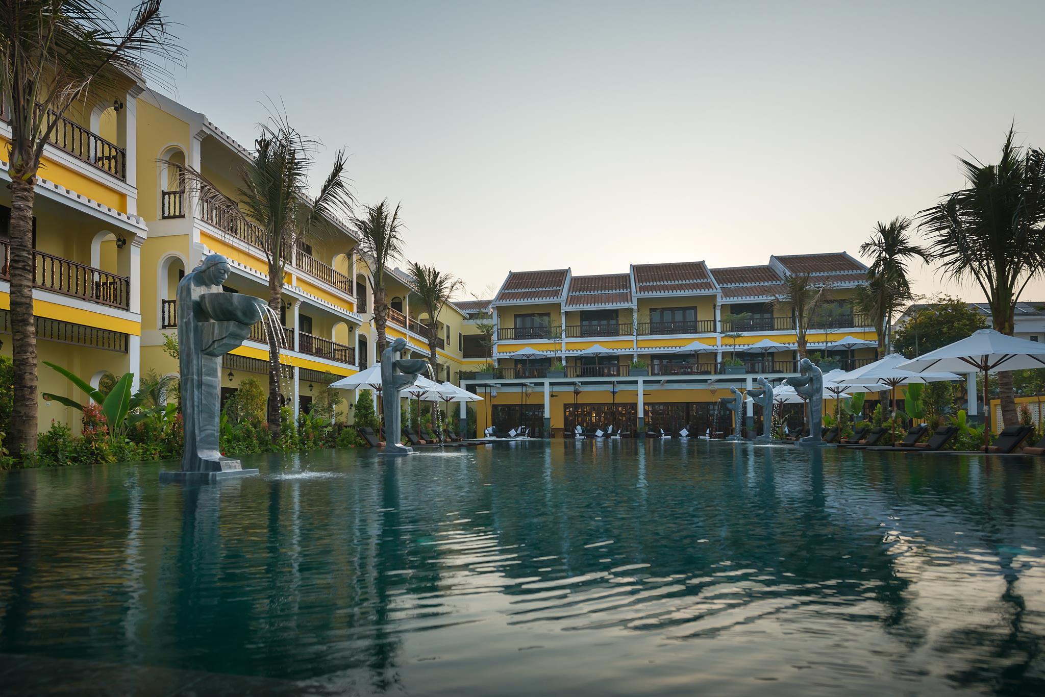 Infinity pool at La Siesta Hoi An reflecting the sunset over lush green rice terraces.