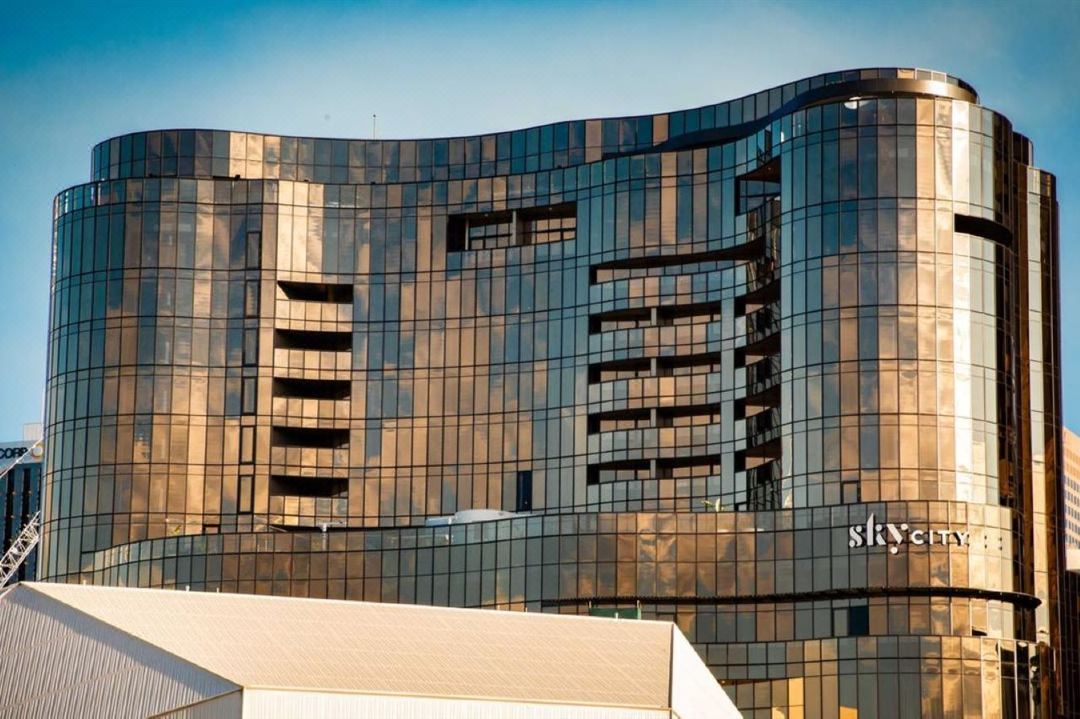 A golden-hued, curved balcony at Eos by SkyCity overlooking the River Torrens at sunset.